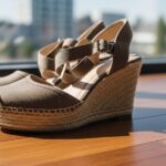 Detailný záber na dámske klinové topánky na drevenej podlahe v mestskom prostredí.